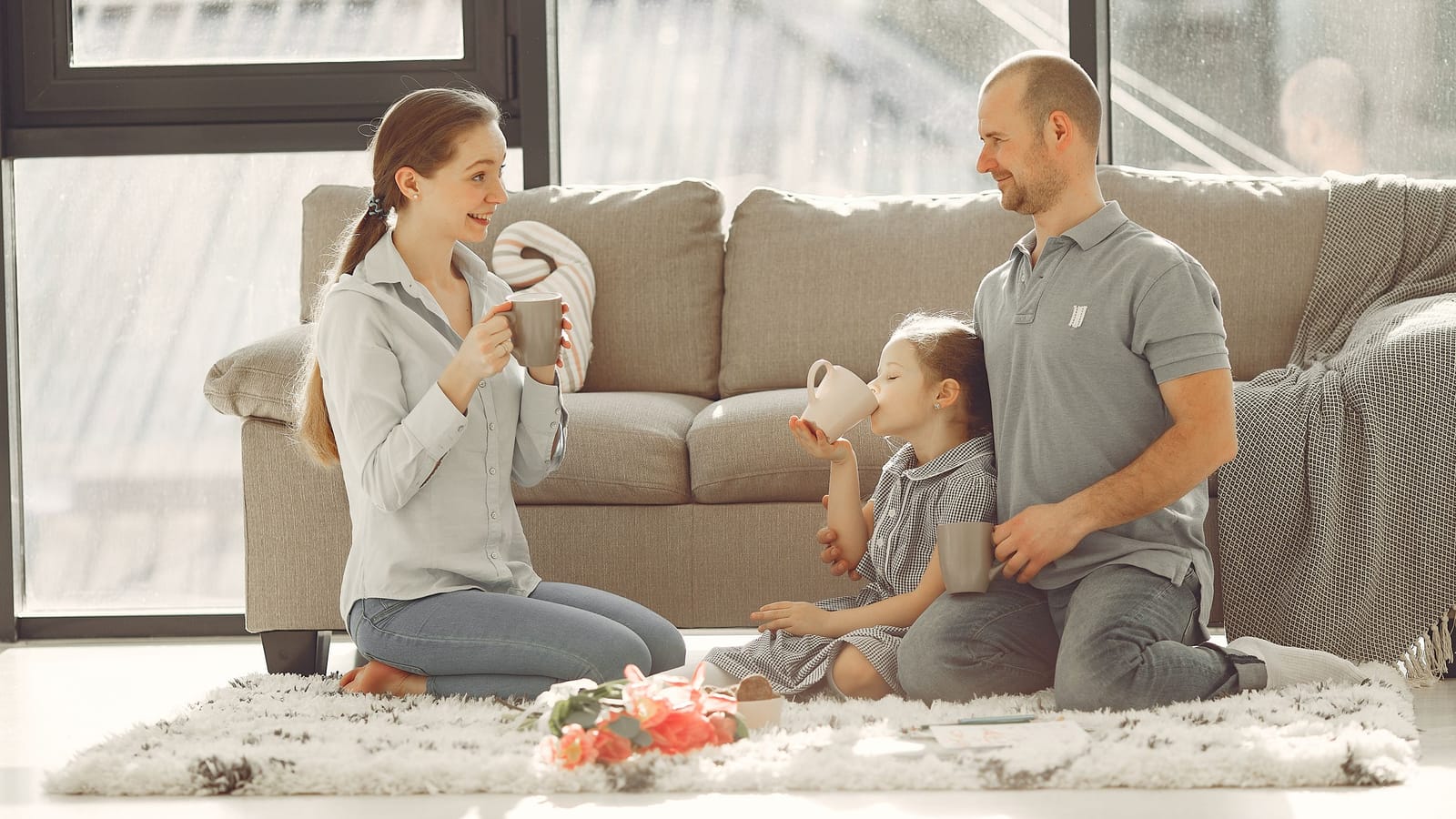 Parents and their daughter drinking hot chocolate together on the living room floor