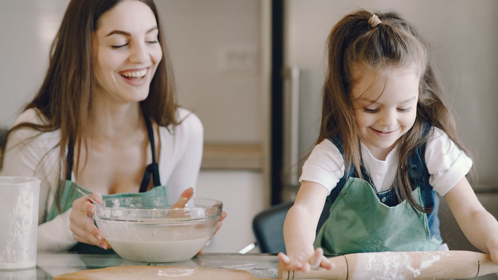 A mum and daughter laughing while baking together